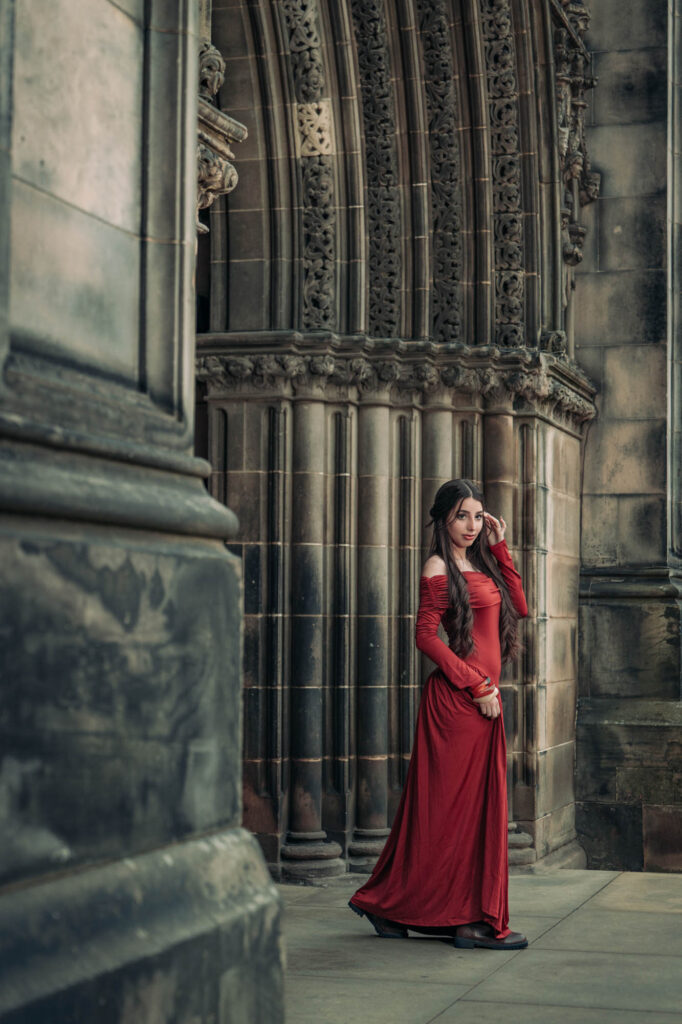 Quinceañera in a red gown among gothic stone arches in Edinburgh