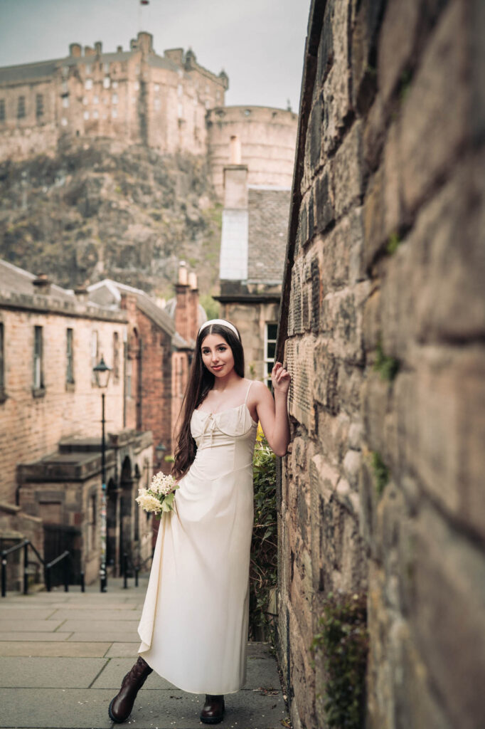 Quinceañera in a white dress in an Edinburgh lane below Edinburgh Castle